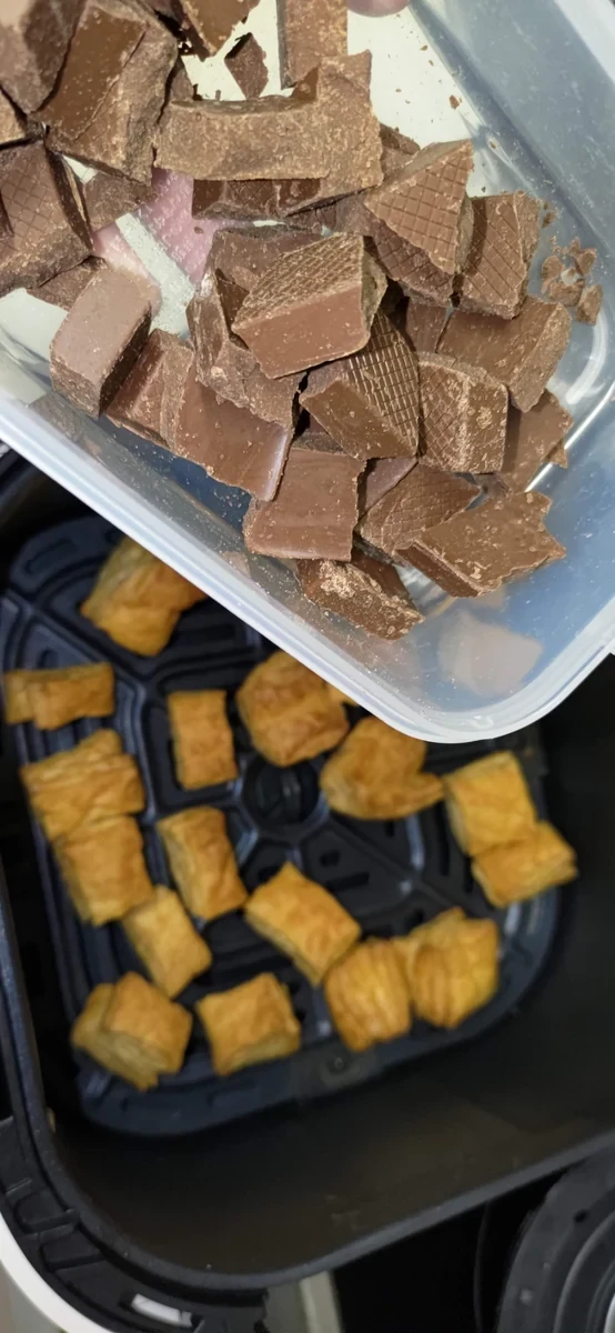 焼いたパイの前に、手で割った板チョコの容器を持った2023年の写真